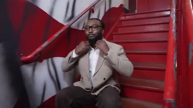 Brian Allen seated on the red stairs of the Bar Fight with Michael Knowles set